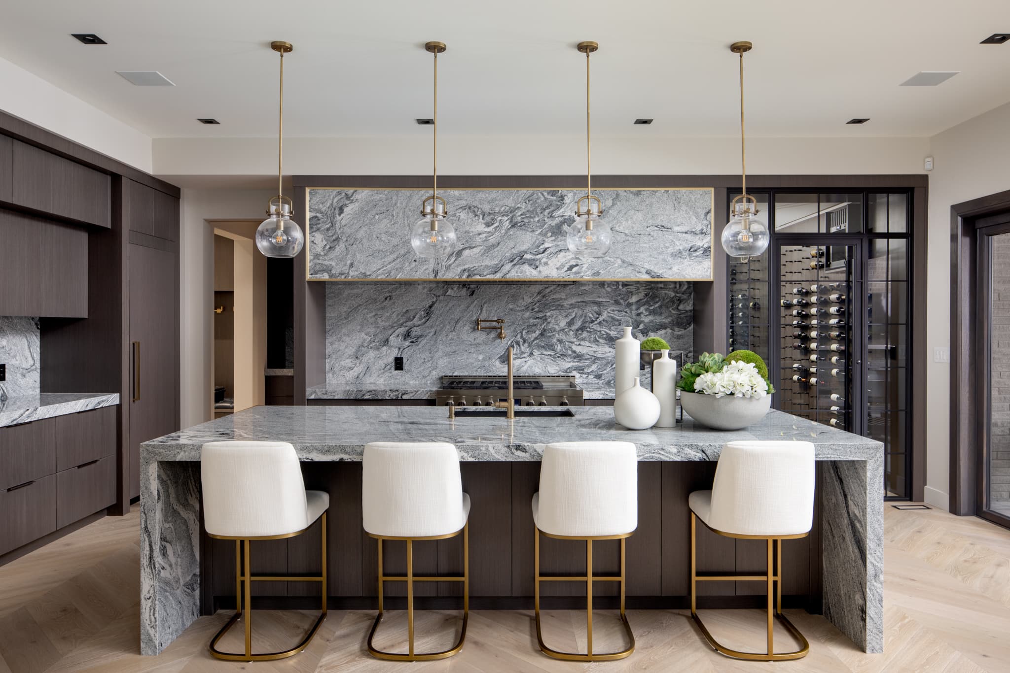 Luxury grey marble kitchen with waterfall island, brass pendant lights, and wine storage in a Timberland Homes custom build in Ontario